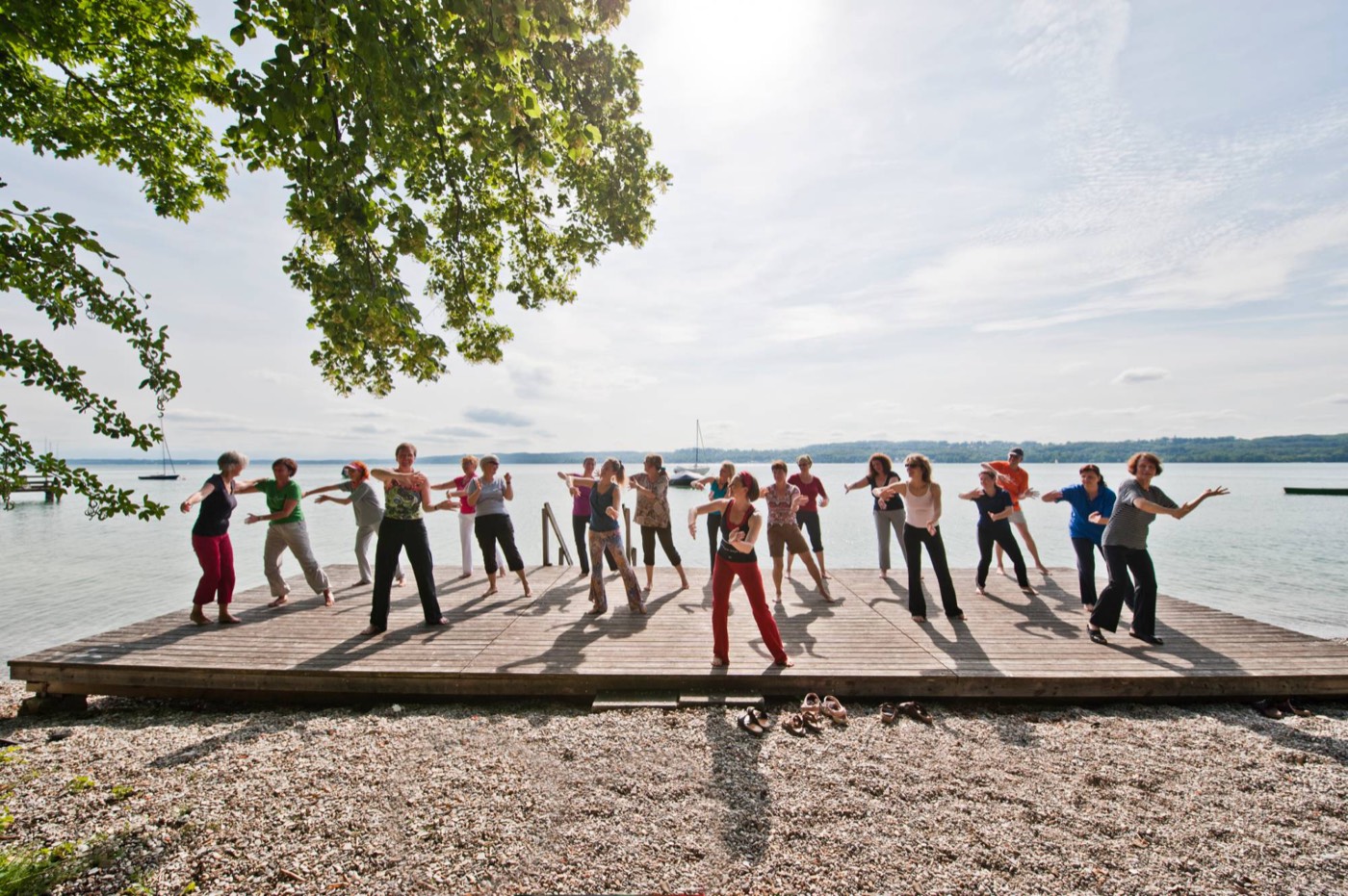 Frauen bewegen sich gemeinsam auf einem Holzsteg am Starnberger See