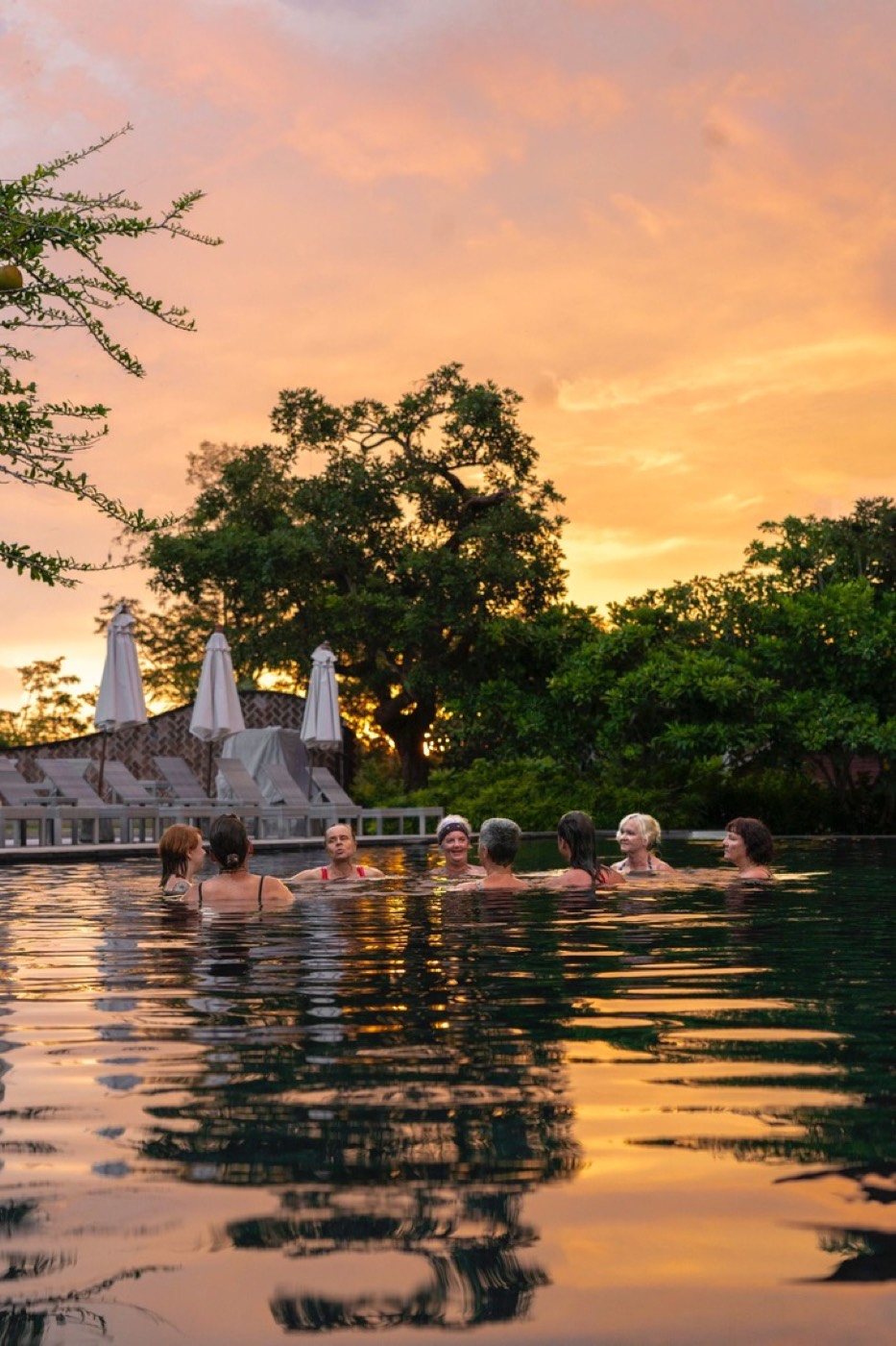 Frauen im Pool bei orangem Sonnenuntergang